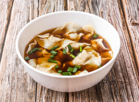 Wonton Soup with Green Onions served in bowl isolated on wooden table side view of hong kong foodの写真素材