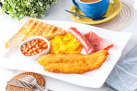 Classic English Breakfast Plate including fried fish, scrambled eggs, sausages, baked beans, toast, and a cup of hot milk tea served in tray isolated on background side view of breakfast mealの写真素材
