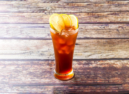 Frozen Lemon Tea topped with lime slice and ice cube served in glass isolated on wooden table side view drinkの写真素材