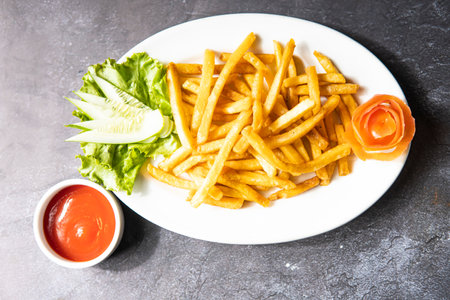French Fries topped with cucumber and lettuce leave and ketchup served in dish isolate on grey background top viewの写真素材