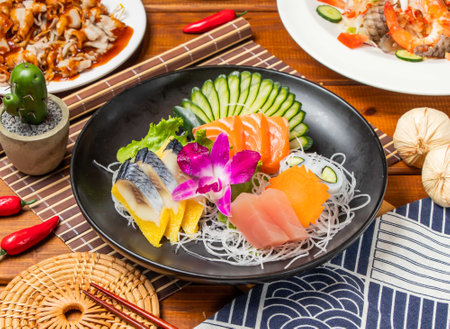 Colorful Comprehensive sashimi with lettuce, cucumber and chopsticks served in dish isolated on table side view taiwanese foodの写真素材