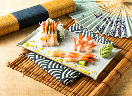 Sweet shrimp sashimi with cucumber served in dish isolated on napkin side view on wooden background of Japanese foodの写真素材