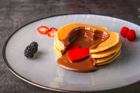 Chocolate Heart Pancakes filled with melted chocolate, strawberries, raspberries, and blackberries served in plate isolated on table side view of indulgent dessertの写真素材