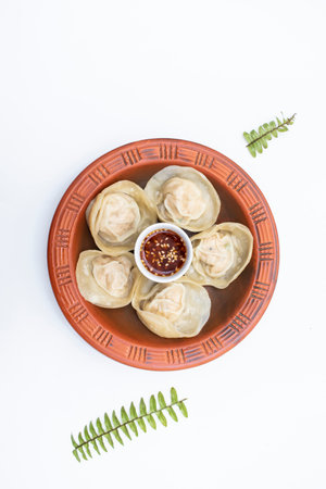 Chicken momo dumplings dim sum with spicy sauce served in clay pot isolated on white background top view of indian, pakistani and bangladeshi foodの写真素材