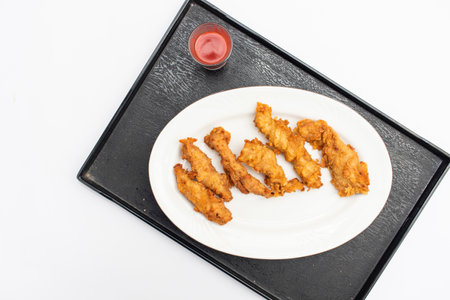 Chicken strips with tomato sauce served in dish on black tray isolated on white background top viewの写真素材