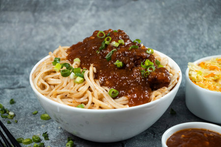Kam heong chicken noodles with Spicy sauce, cabbage salad, green onion and fork served in bowl isolated on grey background closeup side view of asian foodの写真素材