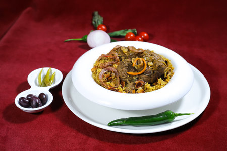 machboos laham or arabic lamb biryani served in pot isolated on red background side view of arabic...