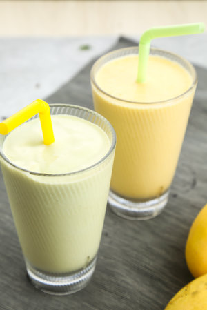 Avocado and Mango Smoothie with straw served in glass isolated on table side view of healthy milkshake drinkの写真素材