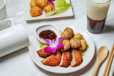 Assorted Fried Snacks with fish cake, Fried squid balls, Dipping Sauce, Taiwanese red bean ice tea served in dish isolated on marble background side view of taiwan foodの写真素材