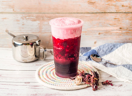 Iced Roselle milk Tea with sugar pot and spoon served in disposable glass isolated on table side viewの写真素材