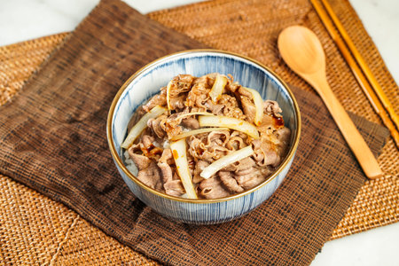 UMAI Beef Donburi with chopsticks and spoon served in bowl isolated on napkin side view of Japanese foodの写真素材