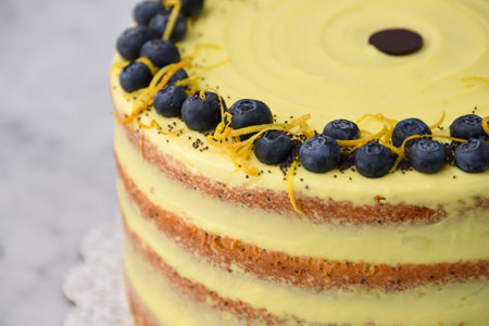 Elegant Lemon Blueberry Layer Cake a vibrant yellow lemon frosting, and a decorative topping of...