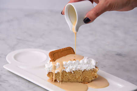 Pouring Milk on Cookies Biscoff Tres Leches Cake Slice with Milk Sauce topped with fluffy whipped...