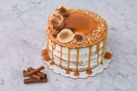 Caramel Fig Drip Cake featuring layers of moist cake drizzled with rich caramel, topped with dried fig slices, cinnamon, and chopped nuts isolated on grey background side view of baked dessertの写真素材