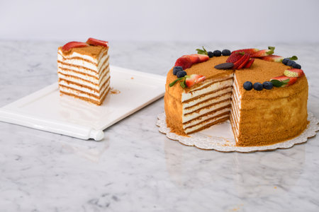 Layered Medovik Honey Cake with strawberry and blueberry slice isolated on grey background closeup side view of delicious cafe dessertの写真素材