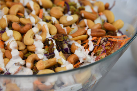Vibrant Broccoli Cashew Salad in glass bowl creamy sauce features broccoli florets, crunchy cashews, shredded carrots, and red cabbage closeup closeup top view of healthy saladの写真素材