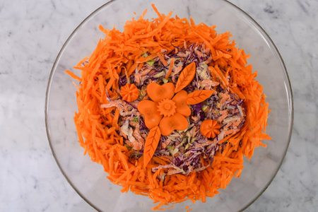 Colorful Carrot and Cabbage Coleslaw Salad in a glass bowl featuring shredded green and red cabbage with a creamy sauce, topped with shredded bright orange carrots closeup top view of classic saladの写真素材