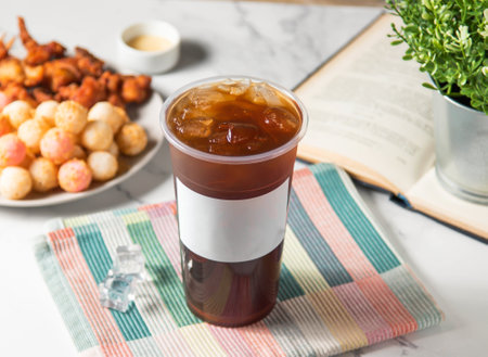 Iced Black tea served in plastic glass with ice cube isolated on napkin side viewの写真素材