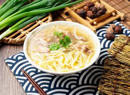 Stir fried duck noodles soup with spring onion, spoon and chopsticks served in bowl isolated on napkin side view on table taiwan foodの写真素材