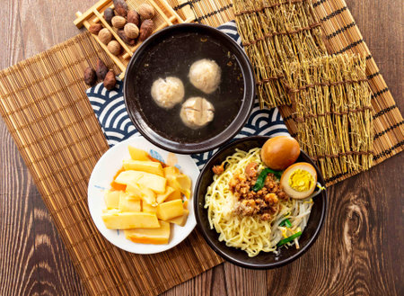 Chinese dry pasta noodles with Crispy bamboo shoots, meatballs soup, minced pork meat, preserved egg and chopsticks served in dish isolated on napkin top view on tableの写真素材