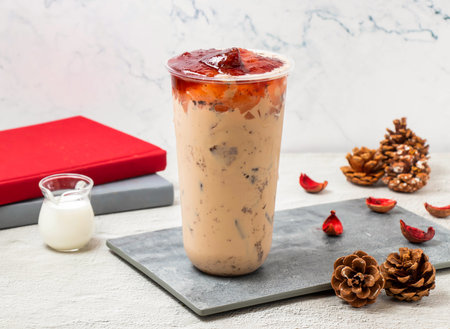 Strawberry milk iced tea served in disposable glass isolated on board side viewの写真素材