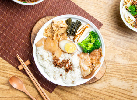 taiwanese lu rou fan include rice, broccoli, boiled egg, tofu, minced pork, braised pork belly, and cabbage served in plate with chopsticks and spoon isolated on wooden board top view of taiwan foodの写真素材