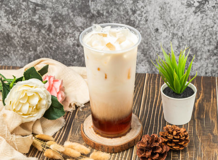 Iced Fresh milk black tea with ice cube served in disposable glass isolated n table side view of taiwanese drinkの写真素材