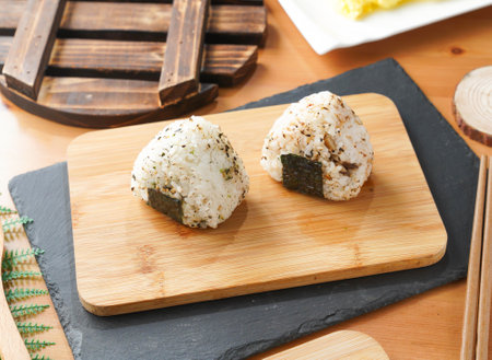 Grilled Rice Ball or Onigiri with Nori and Sesame Seeds served on wooden board with chopsticks side viewの写真素材