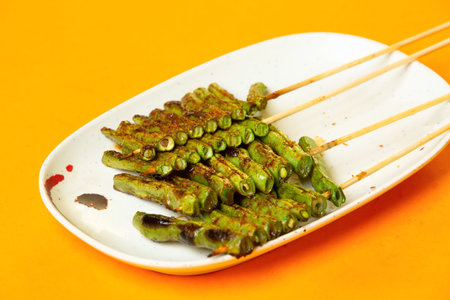 Grilled Green Beans Skewers sticks served in plate isolated on orange background side viewの写真素材