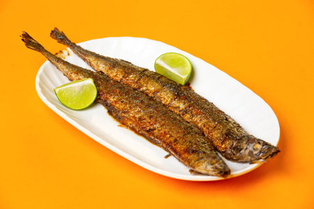 Grilled Capelin Fish or Saury Fish with Lime served in plate isolated on orange background side view of hong kong foodの写真素材