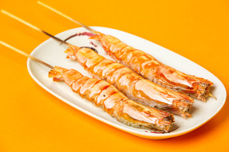 Grilled Tiger Prawns Skewers with salt served in plate isolated on orange background side view of hong kong foodの写真素材