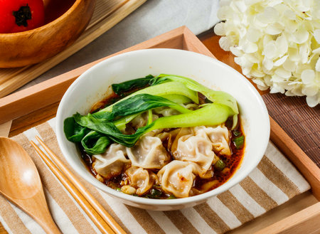 Spicy Szechuan Wonton Soup in bowl served in wooden tray side viewの写真素材