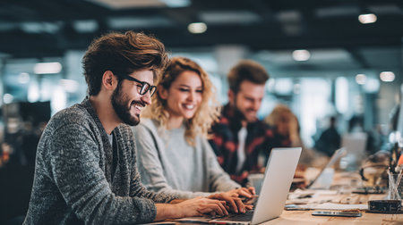 Group of young business people in smart casual wear are using a laptop and smiling while working in the officeの素材