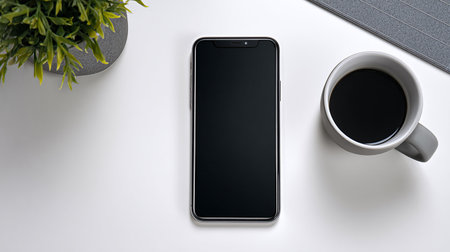 Black smartphone with blank screen and coffee cup on white table, top viewの素材