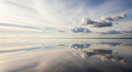beautiful clouds reflected in the calm water of a lake at sunsetの素材