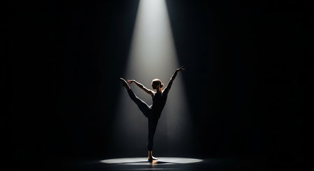 Young beautiful ballerina in black tutu dancing on dark stageの素材
