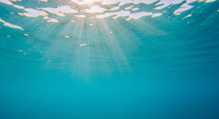 Underwater view of the ocean surface with sunbeams and lens flareの素材