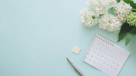 Flat lay of white hydrangea flowers and calendar on blue backgroundの素材