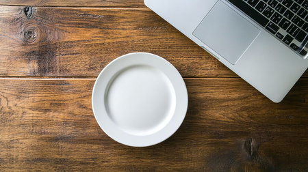 Laptop and empty plate on a wooden table. Top view with copy spaceの素材