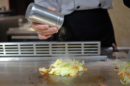Japanese chef deliberately preparing and cooking traditional beef teppanyaki on a hot plateの写真素材