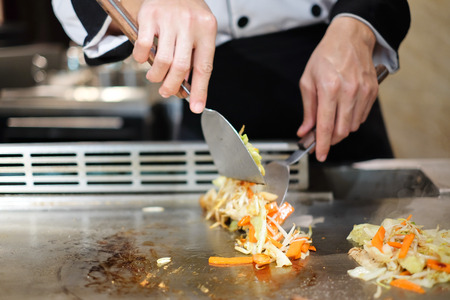 Japanese chef deliberately preparing and cooking traditional beef teppanyaki on a hot plateの写真素材