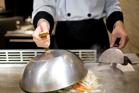Japanese chef deliberately preparing and cooking traditional beef teppanyaki on a hot plateの写真素材