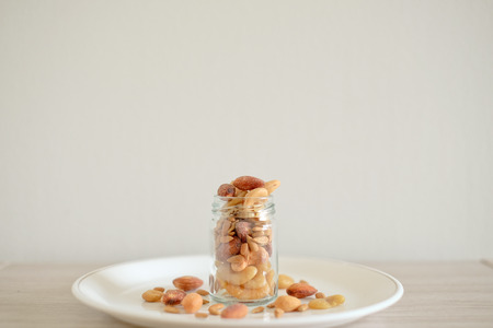Mix of nuts in the glass jars and plate on the tableの写真素材