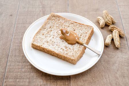a classic slice of whole wheat bread with smooth peanut butter on wooden backgroundの写真素材
