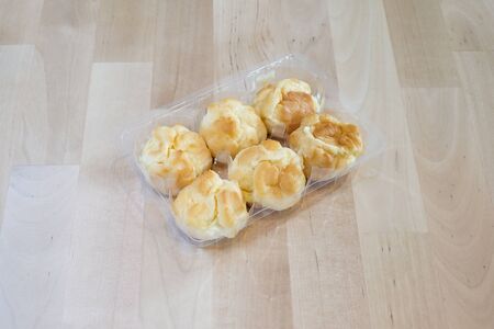 Choux cream in plastic box on wood tableの写真素材