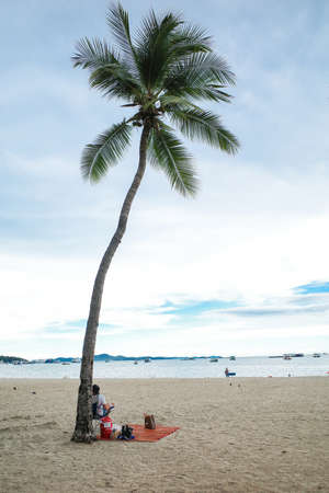 PATTAYA, THAILAND - June 28, 2020: Summer beach vacation, man relaxing on beach chair with coconut treeのeditorial素材