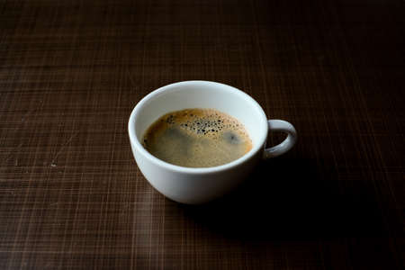 Cup of black coffee on old brown wooden table