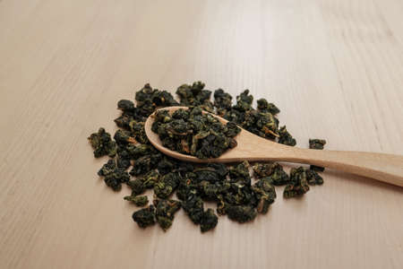 Dried herbal Green tea leaves on a wooden spoon and wooden table background