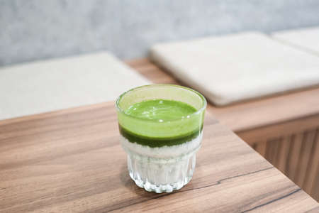 Homemade matcha and milk iced latte on brown wooden tableの写真素材