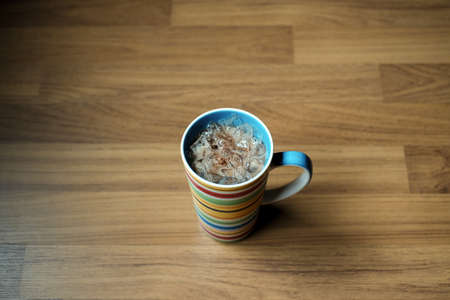 Iced cocoa drink in a ceramic mug on wood background